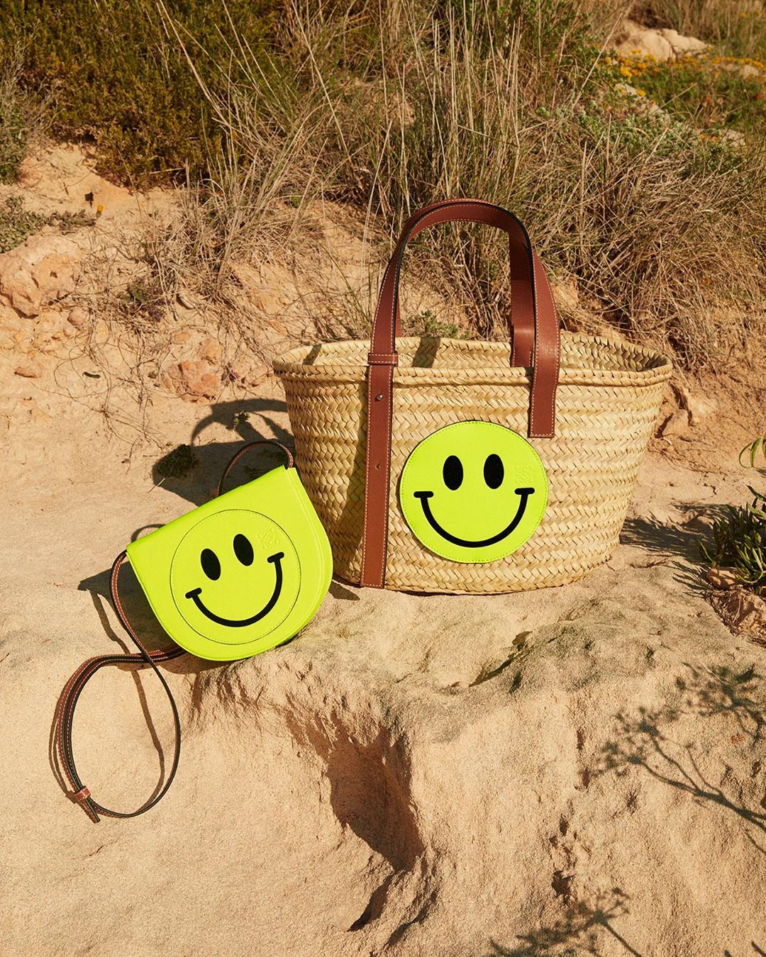 LOEWE - LOEWE Paula’s Ibiza 2020 accessories featuring Smiley®. A basket bag woven from palm leaves is emblazoned with an oversized yellow patch. On the Heel mini the Smiley® is as big as the bag itse...