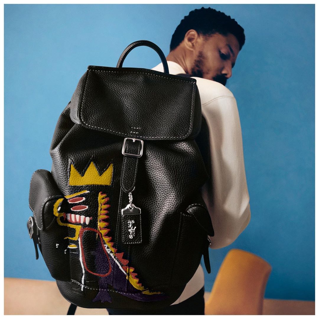 Coach - Monster mash-up. #MichaelBJordan carries the Wells backpack with Basquiat's 'Pez Dispenser' motif. This crowned dino reminds us of our own fierce-but-friendly mascot, Rexy. 

#CoachxBasquiat i...